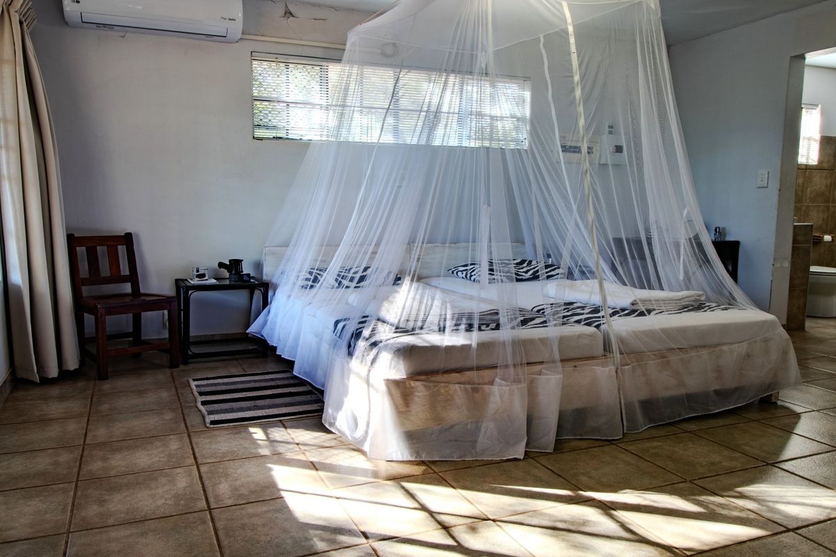 Spacious bedroom featuring tiled flooring, a split-system air conditioner, and direct access to an en-suite bathroom.