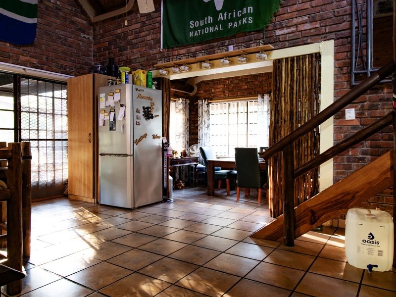 Open plan living area featuring exposed brick walls, ceramic tiled flooring, and a timber staircase leading to an upper level.