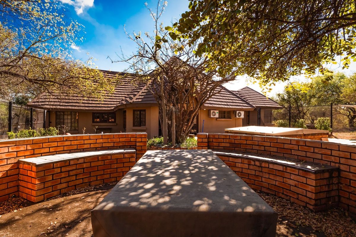 Rear garden area featuring a built-in brick seating arrangement with a central concrete table, set against the rear elevation of the house.