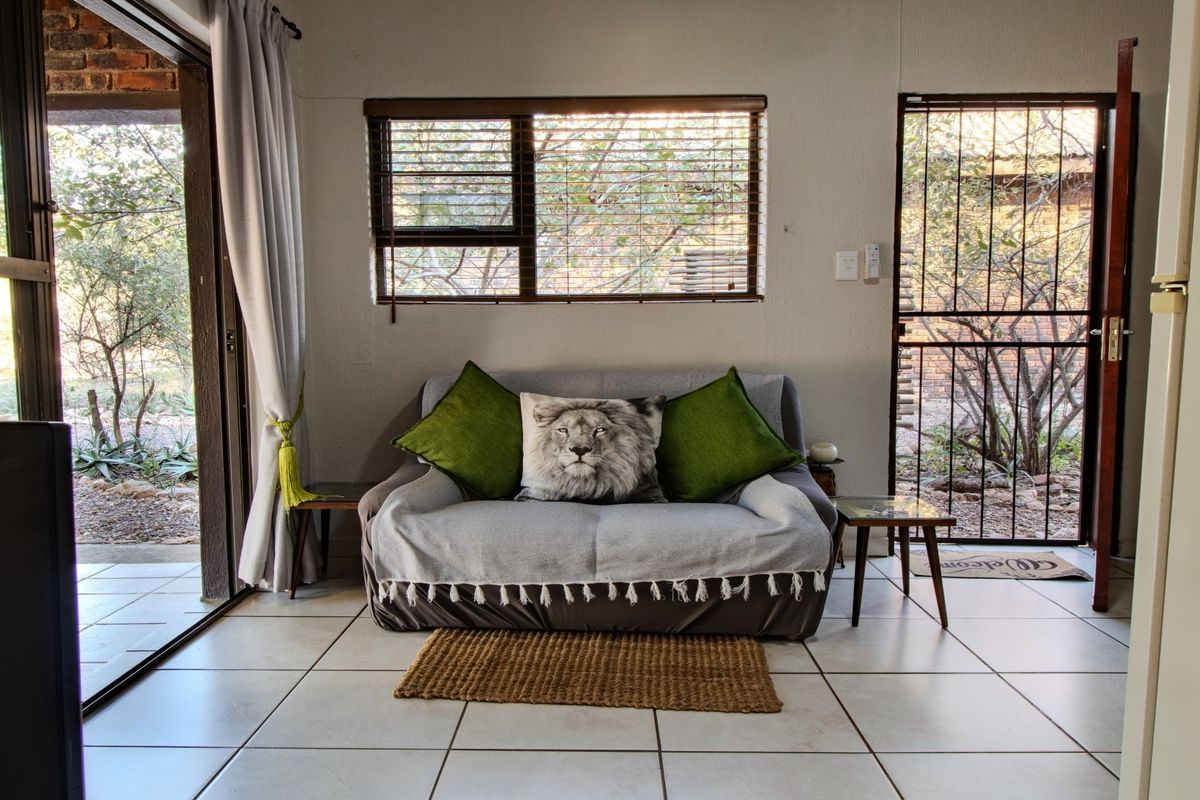 A living area featuring tiled flooring, large sliding glass doors leading to a patio, and a security gate, providing natural light and outdoor access.