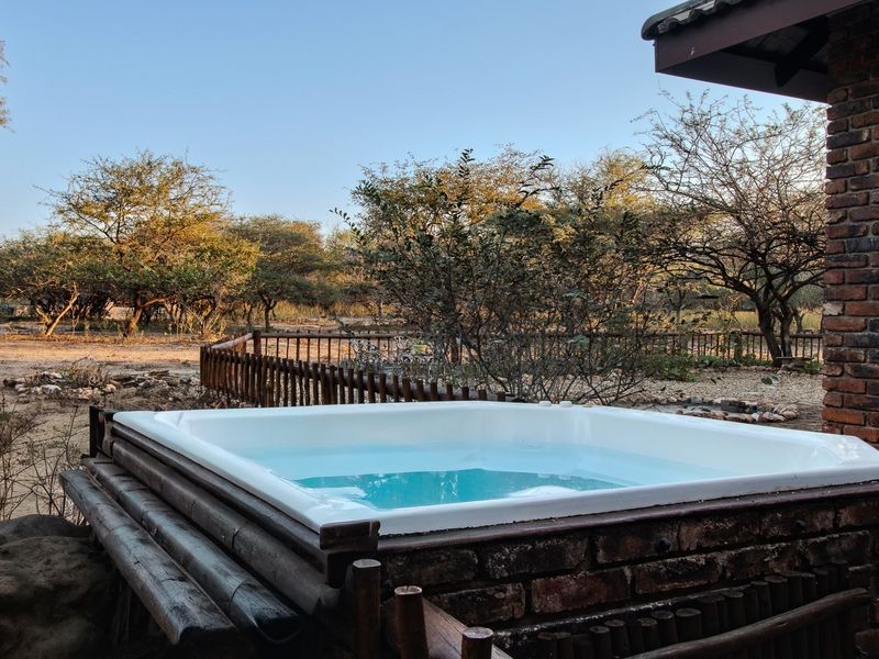 Outdoor built-in spa area featuring brick masonry construction and timber fencing, set against a natural bushveld landscape.