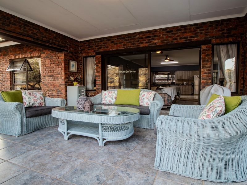 A covered patio area featuring exposed brick walls and tiled flooring, providing a seamless transition to the interior living space through large sliding glass doors.