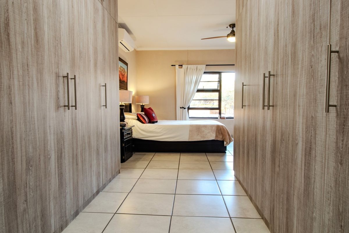 Spacious bedroom featuring extensive built-in cupboards, tiled flooring, a ceiling fan, and an integrated air conditioning unit.