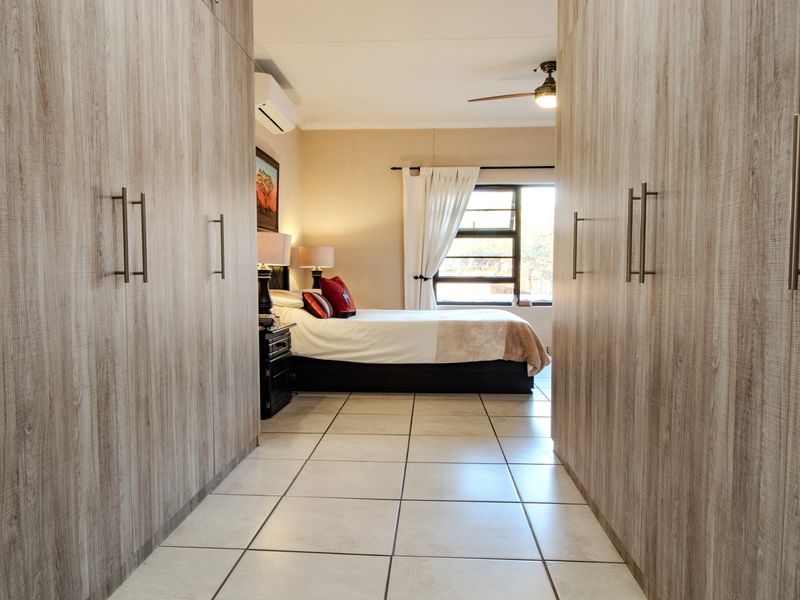 Spacious bedroom featuring extensive built-in cupboards, tiled flooring, a ceiling fan, and an integrated air conditioning unit.