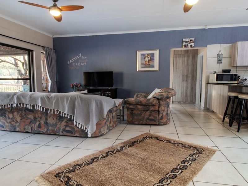 Open-plan living area featuring tiled floors, a kitchen with island seating, and large sliding doors leading to an outdoor patio space.