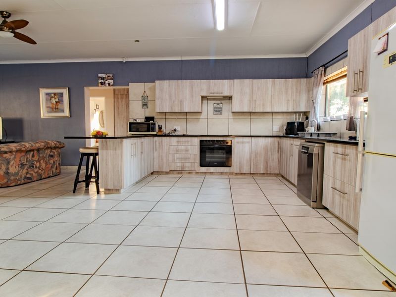 Spacious open-plan kitchen and living area featuring light wood-finish cabinetry, tiled flooring, and integrated kitchen appliances.