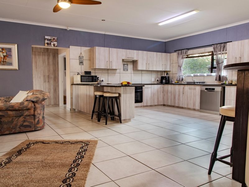 Spacious open-plan kitchen and living area featuring light wood-finish cabinetry, tiled flooring, and functional built-in appliances.
