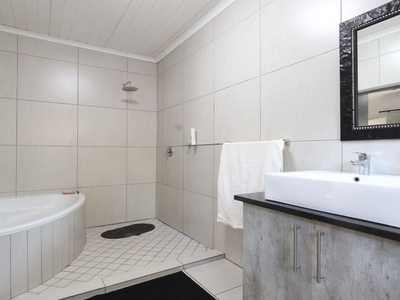 Modern bathroom featuring a corner bathtub, a spacious walk-in shower with tiled finishes, and a contemporary vanity with a countertop basin.