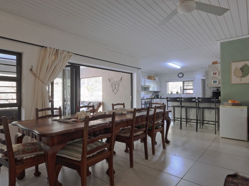 Open-plan living and dining area featuring tiled floors, a breakfast bar, and sliding doors leading to an outdoor patio space.