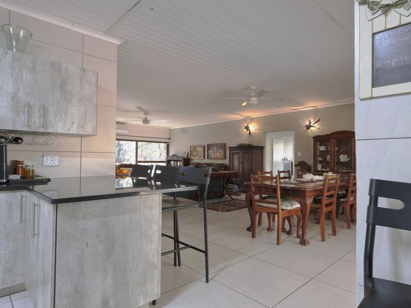 Open plan living and dining area featuring a modern kitchen with stone countertops, tiled flooring, and ceiling fans throughout the space.