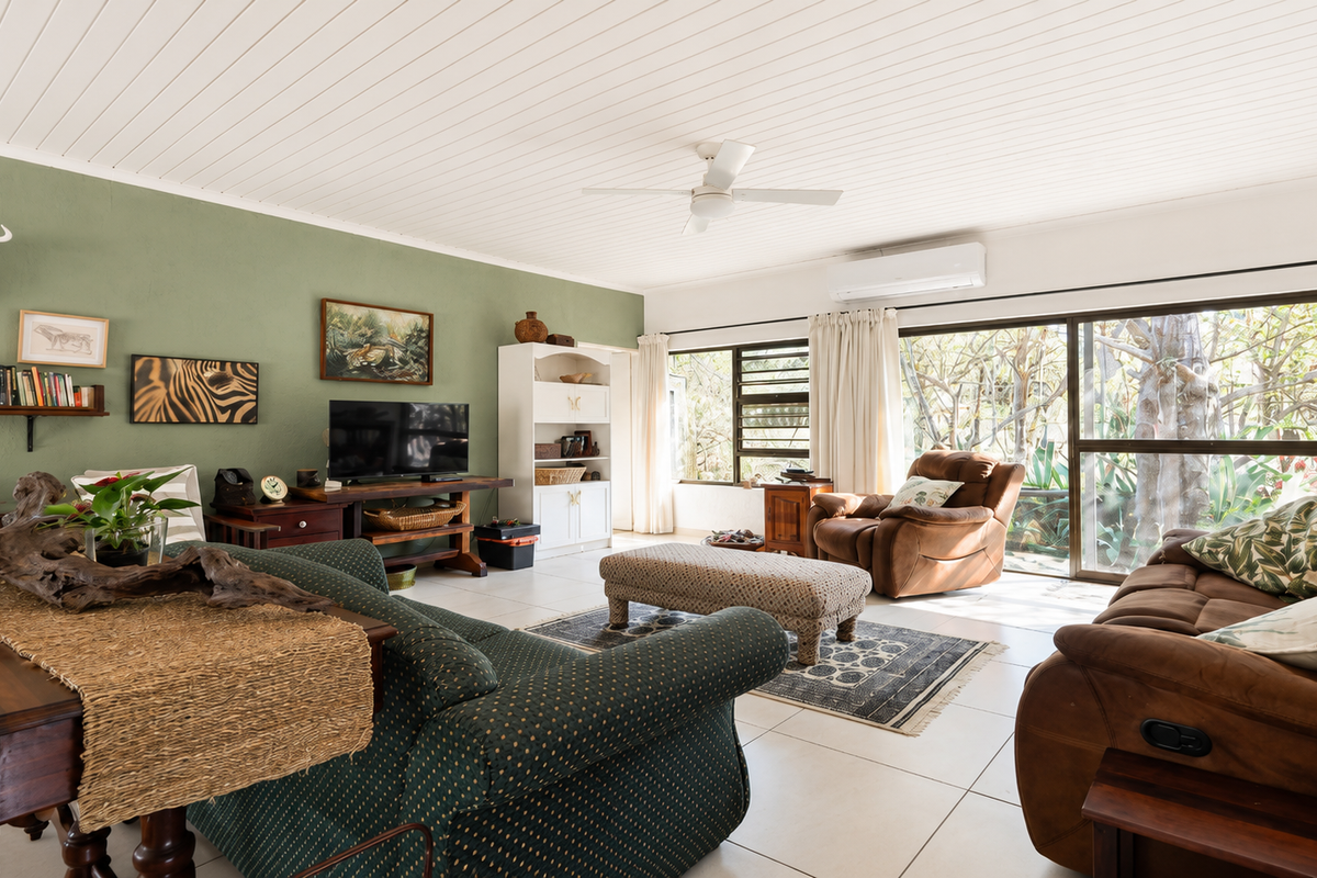 Spacious living room featuring tiled flooring, a ceiling fan, split-system air conditioning, and large sliding glass doors providing natural light and garden views.
