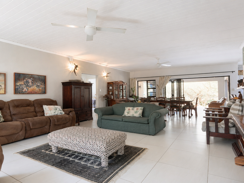 Spacious open-plan living and dining area featuring tiled floors, ceiling fans, and large sliding doors that open to the outdoor space.