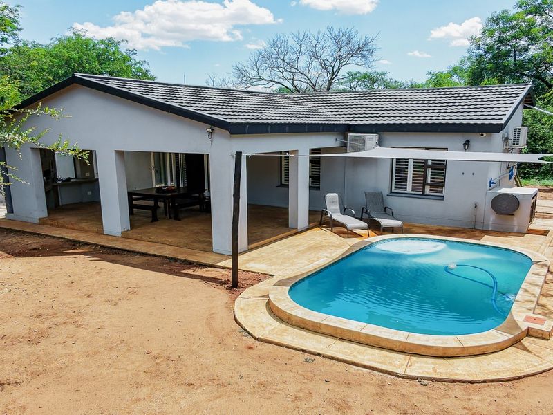 Rear view of the house featuring a covered patio area, a swimming pool with paved surround, and an installed air conditioning unit.