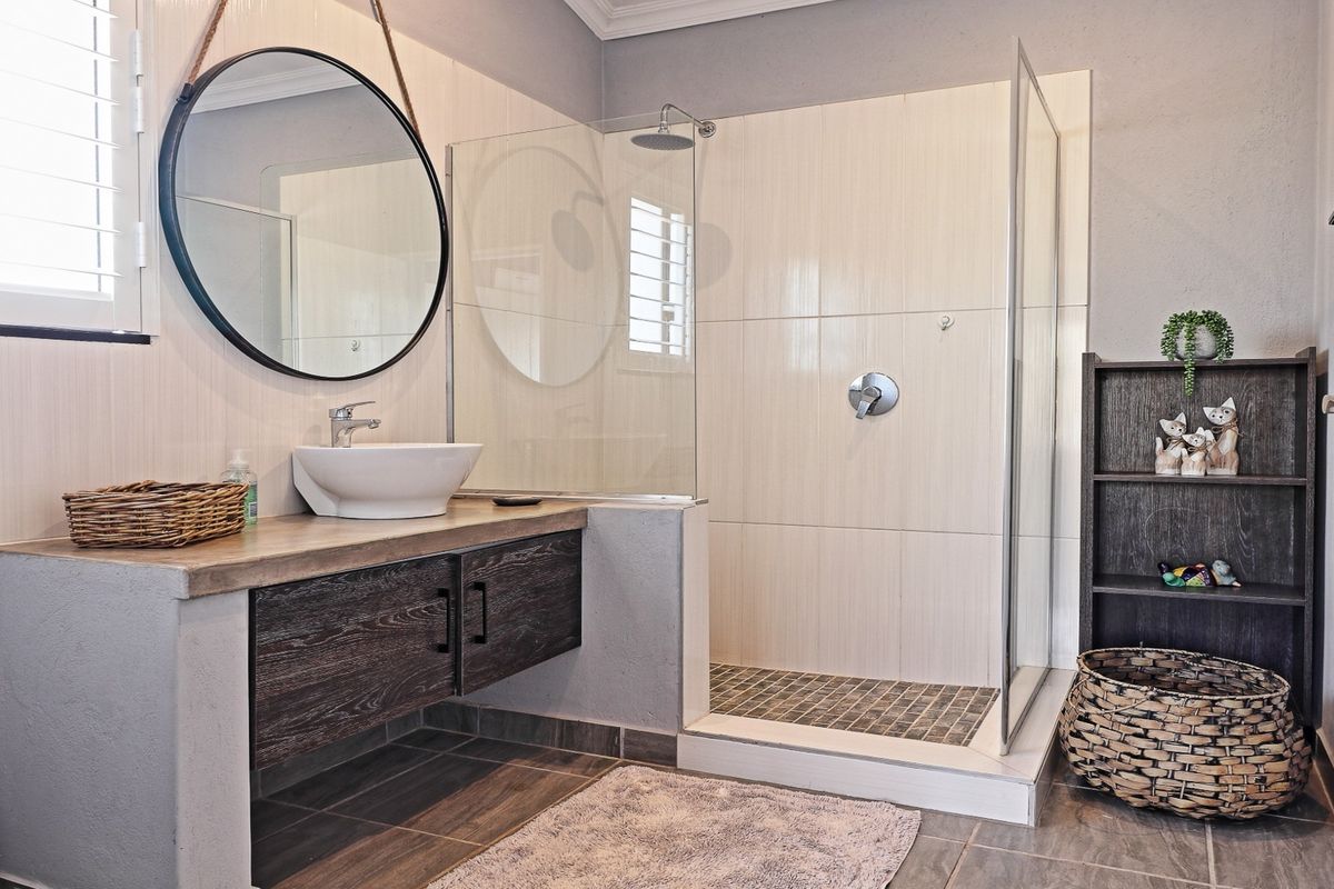 Modern bathroom featuring a walk-in shower with glass screen, vessel sink vanity, and neutral wall tiling.