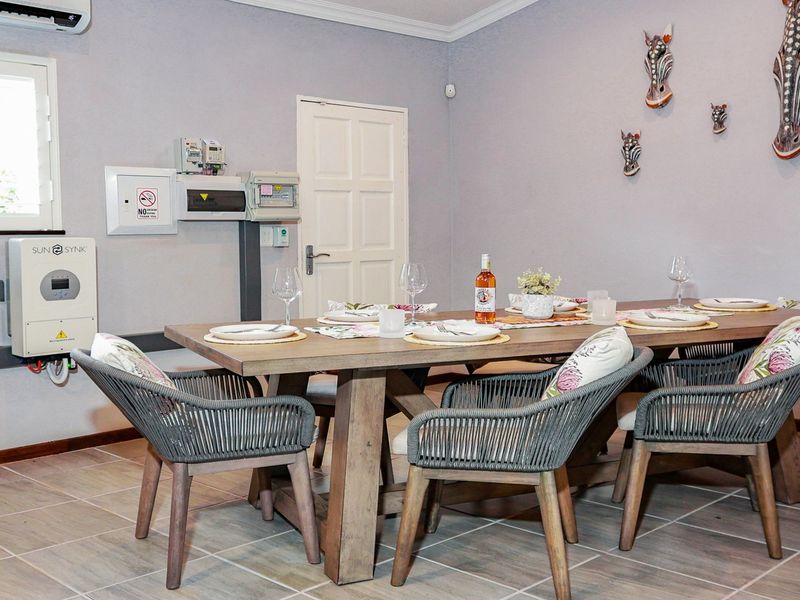 A dining room featuring tiled flooring, a wall-mounted air conditioning unit, and a wall-mounted solar inverter system.