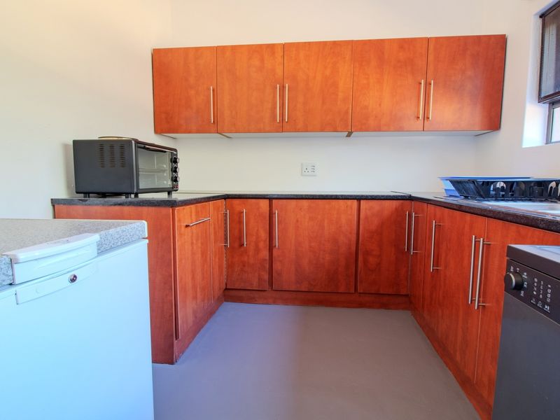 A functional kitchen featuring wood-finish cabinetry, granite countertops, and a stainless steel sink, providing a practical workspace with ample storage.