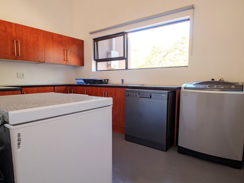 Functional laundry room featuring built-in wooden cabinetry, dark laminate countertops, a sink, and dedicated space for appliances.