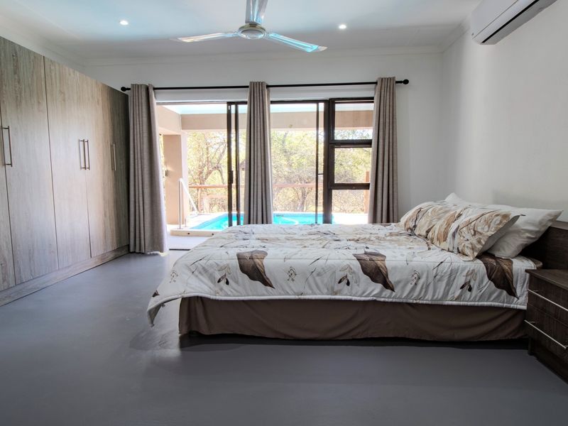 Spacious bedroom featuring extensive built-in cupboards, a ceiling fan, air conditioning, and sliding glass doors providing direct access to the pool area.