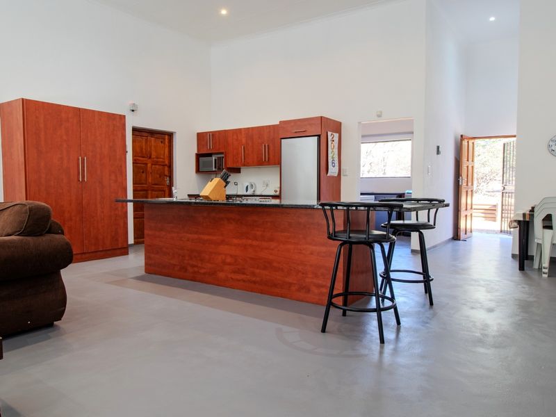 Spacious open-plan living area featuring a kitchen with a central island, granite countertops, and polished concrete flooring, leading to an outdoor entrance.