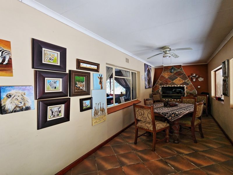 Spacious living area featuring terracotta-style tiled flooring, a built-in fireplace with decorative tiling, and a ceiling fan.
