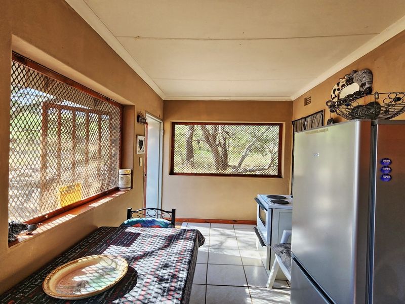 A functional kitchen area featuring tiled flooring, security screen windows, and a freestanding stove, offering a practical layout with potential for modernization.