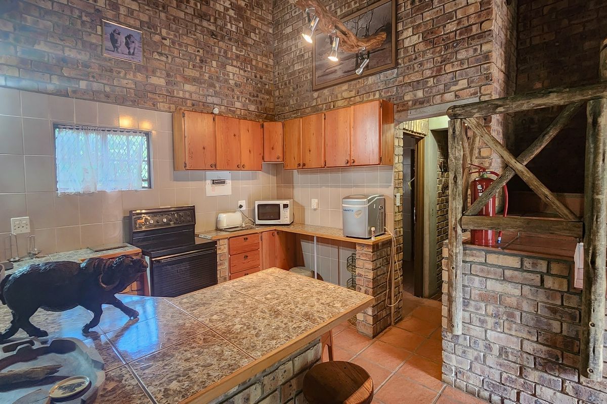 Rustic kitchen featuring exposed brick walls, wooden cabinetry, tiled countertops, and a functional layout with integrated stove and tiled flooring.