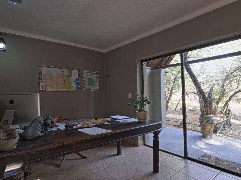 A functional home office featuring ceramic floor tiles and a large sliding glass door providing direct access to the outdoor area.