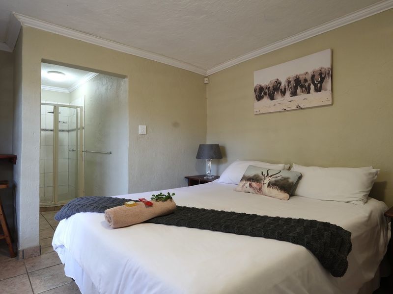 A bedroom featuring tiled flooring, crown molding, and an attached en-suite bathroom with a shower enclosure.
