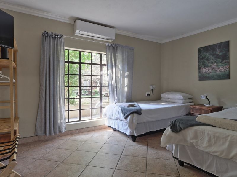 A bedroom featuring tiled flooring, a split-system air conditioner, and a large steel-framed window providing natural light.