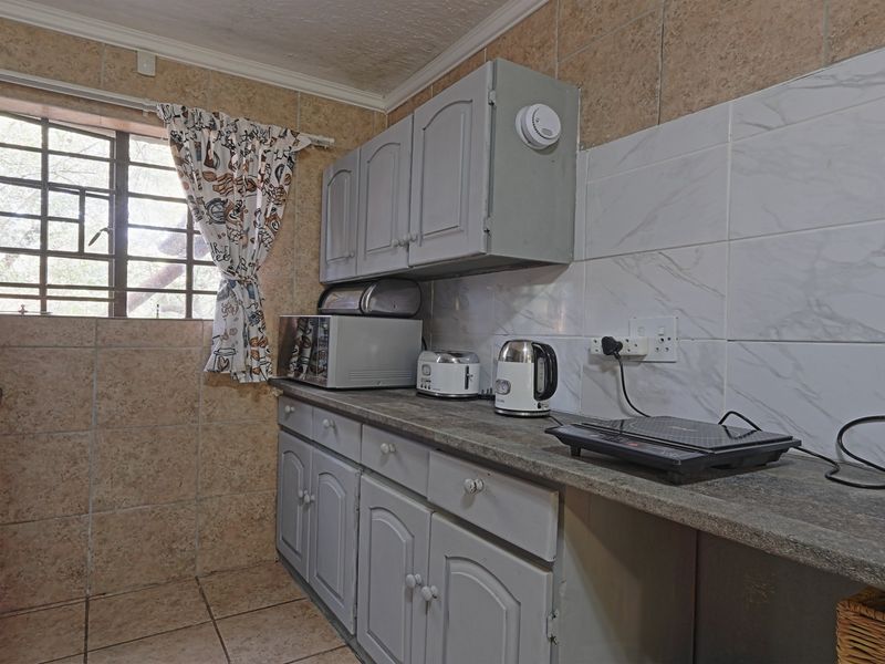 A compact kitchen featuring built-in cabinetry, stone-look countertops, and tiled finishes, offering a functional space with potential for modern updates.