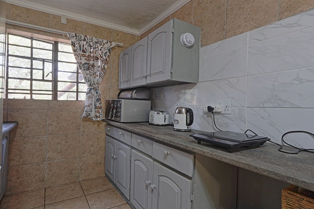 A compact kitchen featuring built-in cabinetry, stone-look countertops, and tiled finishes, offering a functional space with potential for modern updates.