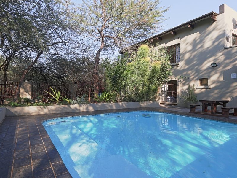 Outdoor pool area featuring a tiled surround, retaining wall, and established garden setting, providing a private space for relaxation and entertainment.