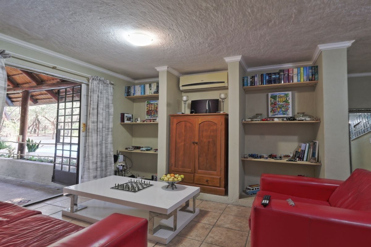 A living room featuring built-in shelving, tiled flooring, and a sliding glass door providing access to an outdoor patio area.