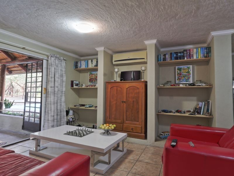 A living room featuring built-in shelving, tiled flooring, and a sliding glass door providing access to an outdoor patio area.