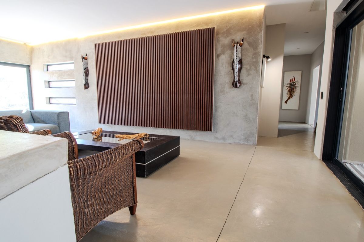 Modern living room featuring polished concrete floors, a striking timber slat wall feature, and recessed ambient lighting with access to outdoor areas.