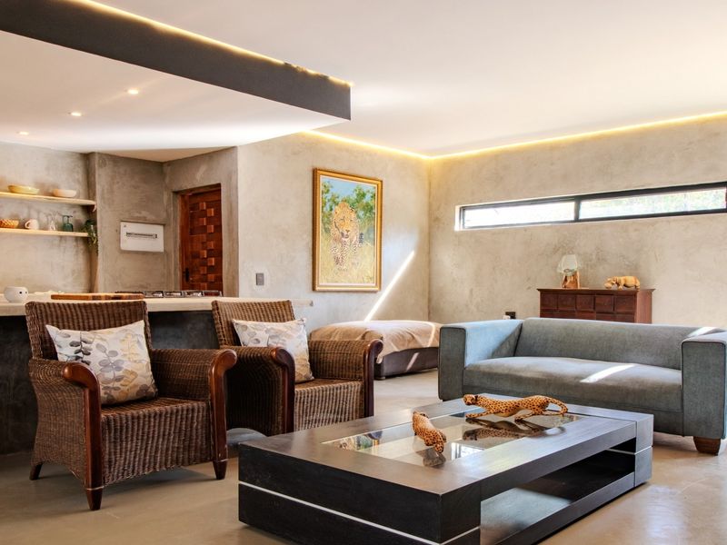 Modern open-plan living area featuring polished concrete floors, recessed ambient lighting, and a sleek concrete kitchen island with floating timber shelving.