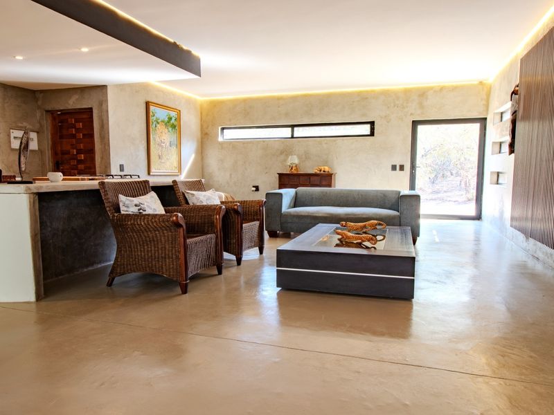 Spacious open-plan living area featuring polished concrete floors, modern timber slat wall accents, and integrated recessed lighting with a seamless kitchen transition.