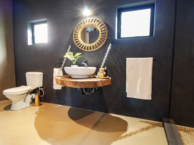 A modern bathroom featuring a unique suspended wooden vanity with a vessel sink, dark walls, and a separate shower area.