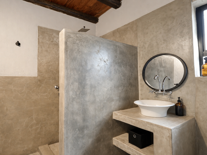 Modern bathroom featuring a polished concrete vanity, vessel sink, walk-in shower, and exposed timber ceiling beams with a contemporary industrial aesthetic.