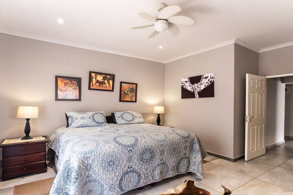 A well-maintained bedroom featuring neutral wall tones, tiled flooring, a ceiling fan, and recessed lighting, offering a clean and comfortable living space.