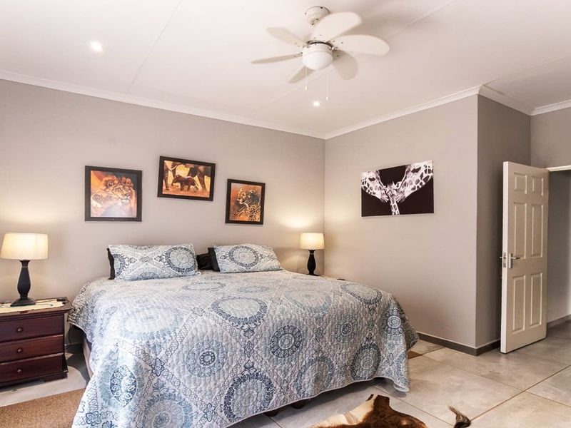 A well-maintained bedroom featuring neutral wall tones, tiled flooring, a ceiling fan, and recessed lighting, offering a clean and comfortable living space.