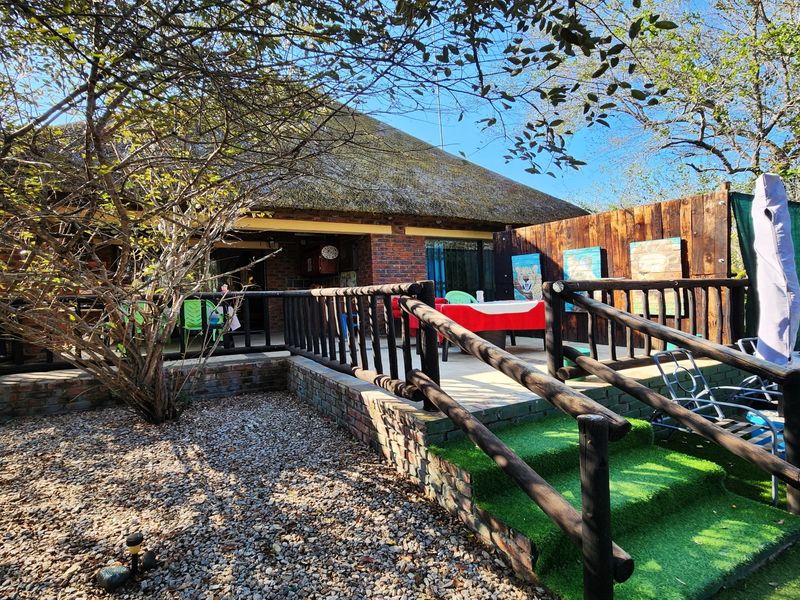 Outdoor patio area featuring a thatched roof, brick exterior walls, and timber railings, providing a rustic space for outdoor living.