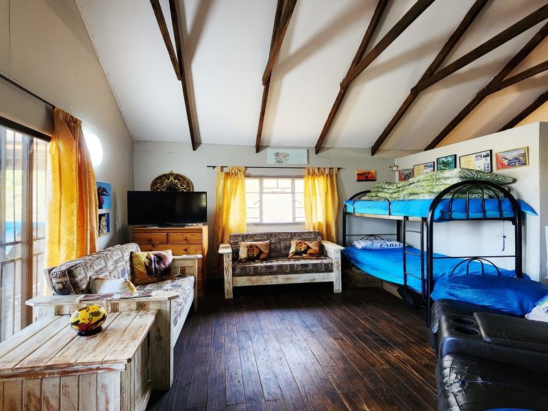 Spacious bedroom featuring exposed timber ceiling beams, dark wood flooring, and a sliding glass door providing access to the exterior.