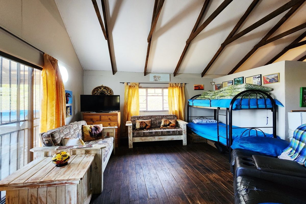 Spacious bedroom featuring exposed timber ceiling beams, dark wood flooring, and a sliding glass door providing access to the exterior.