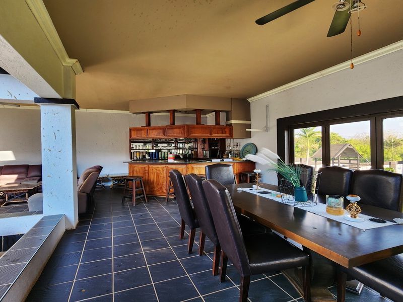 Spacious covered patio featuring a built-in bar, tiled flooring, and large sliding doors opening to the garden, ideal for outdoor entertaining.