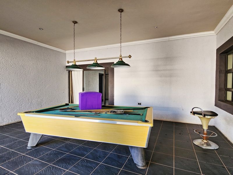 A covered patio or entertainment area featuring dark tiled flooring, recessed lighting, and decorative pendant lights, suitable for a recreational space.