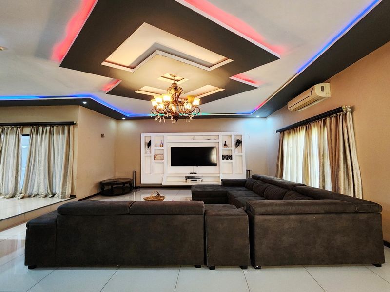Spacious living room featuring a decorative recessed ceiling with integrated LED lighting, a built-in media wall unit, and split-system air conditioning.