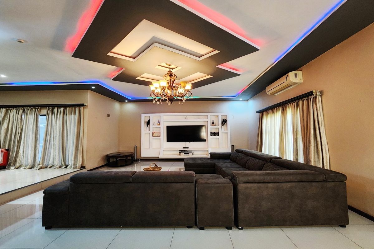 Spacious living room featuring a decorative recessed ceiling with integrated LED lighting, a built-in media wall unit, and split-system air conditioning.