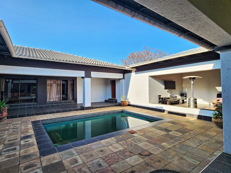 Spacious outdoor entertainment area featuring a swimming pool, covered patio space, and tiled flooring, ideal for relaxation and hosting guests.