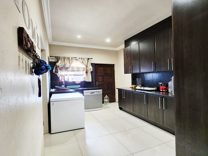 A functional kitchen featuring dark wood cabinetry, tiled flooring, and a tiled backsplash, providing ample storage and workspace.